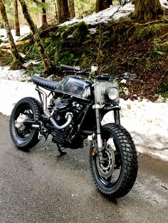 a motorcycle is parked on the side of the road in the snow near some trees