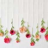 pink and red flowers hanging from the side of a white brick wall