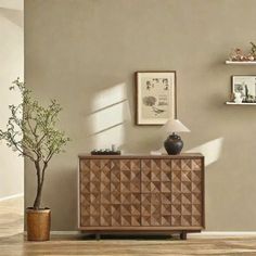 a living room with a wooden cabinet and potted plant on the sideboard next to it