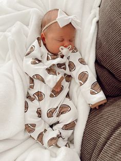 a baby wrapped in a blanket sleeping on top of a couch