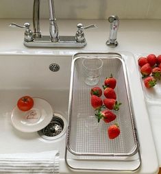 strawberries are sitting on the edge of a kitchen sink, next to a strainer