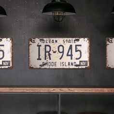 three license plates are hanging on the wall above a shelf with stools and lamps