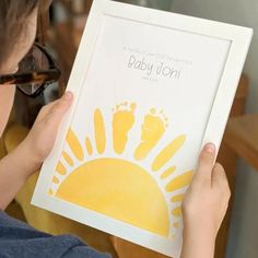 a person holding up a baby's hand and foot print