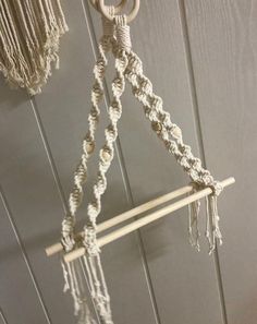 a macrame hanging from the ceiling with two wooden poles and ropes attached to it