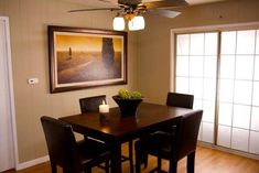 a dining room table with four chairs and a painting on the wall