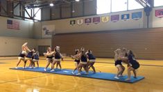 a group of cheerleaders standing on top of a blue mat in a gym