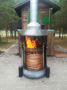 a large metal stove sitting on top of a brick floor next to a forest filled with trees