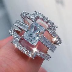 a woman's hand holding an engagement ring with two rows of diamonds on it