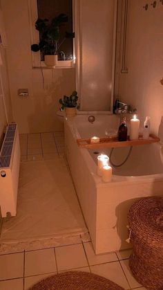 a bath tub sitting next to a window with candles on top of it and a rug in front of it