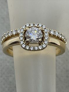 a gold ring with a white diamond surrounded by small round cut diamonds on the band