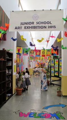 the entrance to an art exhibition with people walking through it and colorful decorations hanging from the ceiling