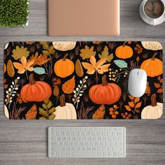 a computer mouse pad with pumpkins, leaves and acorns on it next to a keyboard