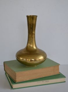 a gold vase sitting on top of two green book's next to each other