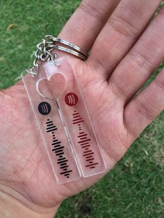 a person holding two different types of keys in their hand with grass in the background