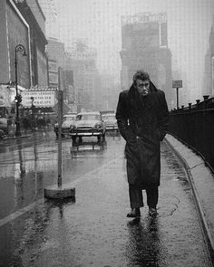 black and white photograph of man walking in the rain