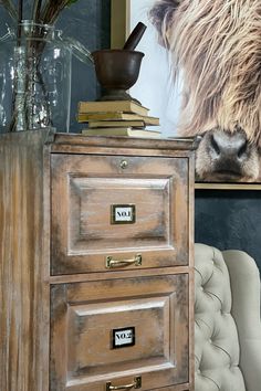 a wooden cabinet with two drawers next to a chair and a painting on the wall