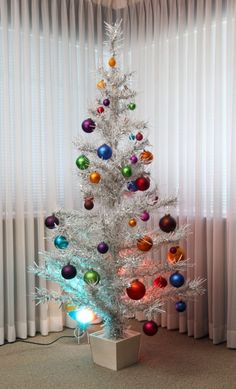 a white christmas tree decorated with multicolored ornaments