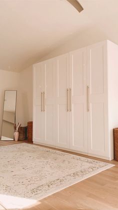 an empty room with white cabinets and a large rug on the floor in front of it