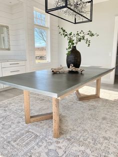 a dining room table with a vase on it and a rug in front of it