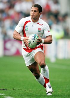 a man running with a soccer ball in his hand on a field during a game