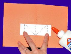 someone is making an origami envelope out of construction paper and glue with their fingers