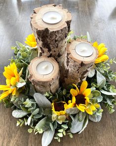 three candles are sitting on some wood with sunflowers and greenery around them