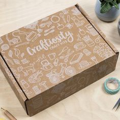 an open box sitting on top of a wooden table next to scissors and other crafting supplies