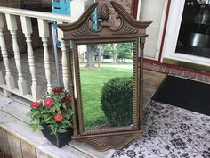 a mirror sitting on top of a porch next to a planter filled with flowers