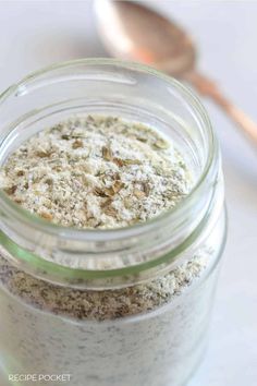 a jar filled with food sitting on top of a table next to a wooden spoon