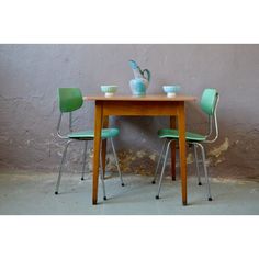 two green chairs sit at a small table with a vase on it and another chair is next to the table