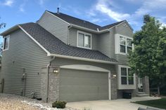 a gray house with two garages and trees in the background