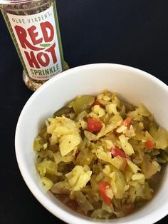 a white bowl filled with chopped vegetables next to a bottle of red hot sprinkle