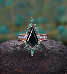 an image of a black stone ring on top of a piece of rock with turquoise stones