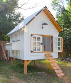 a small white house with stairs leading up to the roof and windows that are open