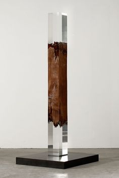 a tall glass sculpture sitting on top of a wooden table next to a white wall