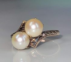 Pearl ring; Lovely genuine Art Deco pearl engagement ring in 14K rose gold. The two pearls are set in a romantic "toi et moi" (you and me) setting. Pearls were often used in engagement and betrothal jewelry at the turn of the century prior to diamonds becoming very popular. The pearls are in beautiful condition and have beautiful lustre. The shoulders of the ring have lovely hand etched detail that is still beautiful and crisp and the prongs are old gothic claw prongs in the Victorian fashion, j Art Deco Pearl, Japanese Stamp, Japanese Pearls, Engagement Ring Art Deco, Pearl Engagement Ring, Engagement Ring Inspiration, June Birthday, Bypass Ring, Art Deco Engagement