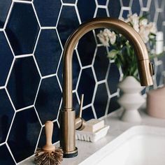 a white sink sitting under a faucet next to a blue tiled kitchen wall