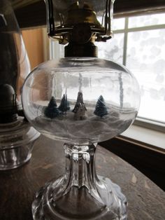 there is a glass bowl with trees in it on top of a table next to a window