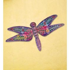 a colorful dragonfly sitting on top of a yellow wall