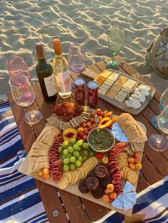 a picnic table with wine, cheese and crackers on the beach