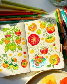 an open notebook with tomatoes on it next to some colored pencils and other art supplies