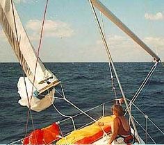 a man sitting on top of a sailboat in the ocean next to another boat