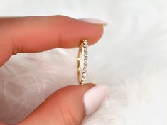 a woman's hand holding a gold ring with three small diamonds on the side