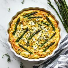 asparagus and cheese quiche in a white dish on a marble countertop