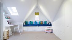 an attic bedroom with white walls and blue cushions