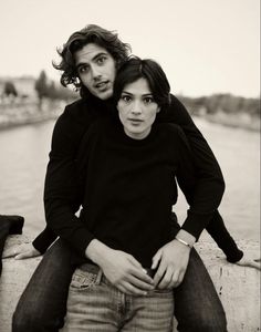 black and white photograph of two people sitting next to each other on a stone wall