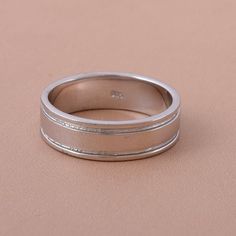 a wedding band is shown on top of a plain surface, with the ring slightly bent to the side