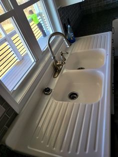 a kitchen sink with two faucets and a window in the backround