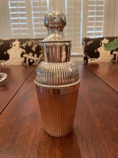 a silver vase sitting on top of a wooden table