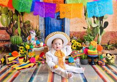 a baby wearing a sombrero sitting in front of a table with mexican decorations